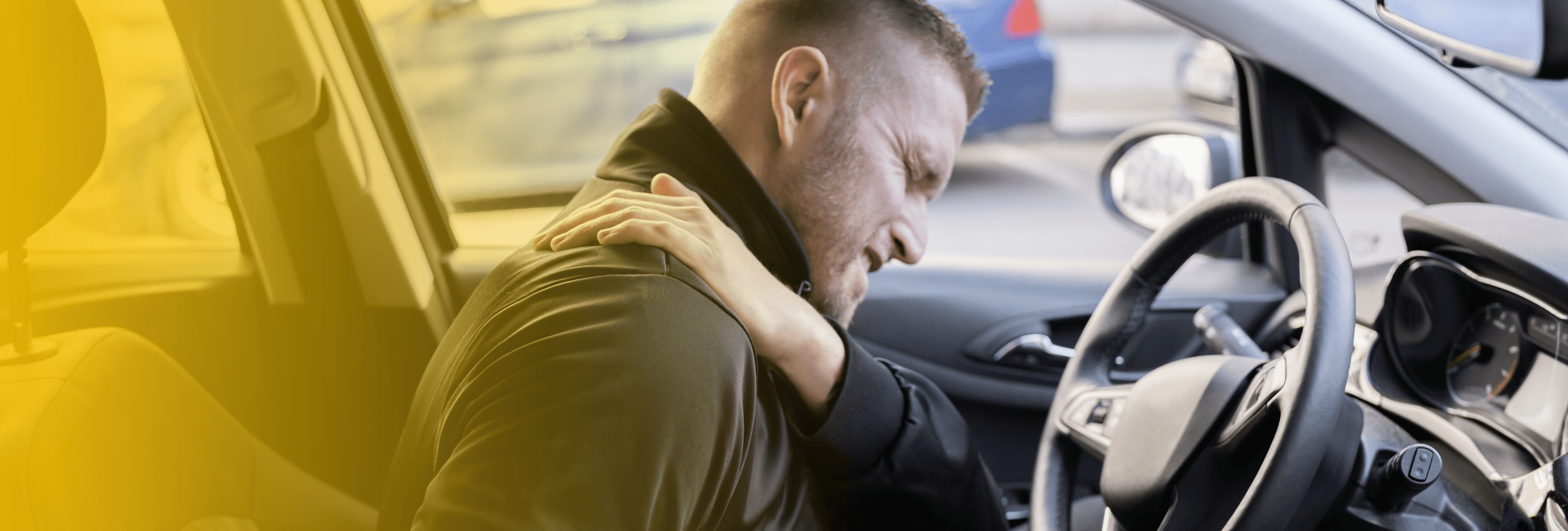 Man in driver’s seat clutching shoulder in pain