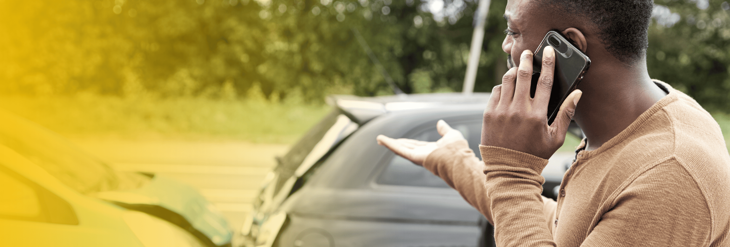 Man on phone near crash scene, gesturing in frustration